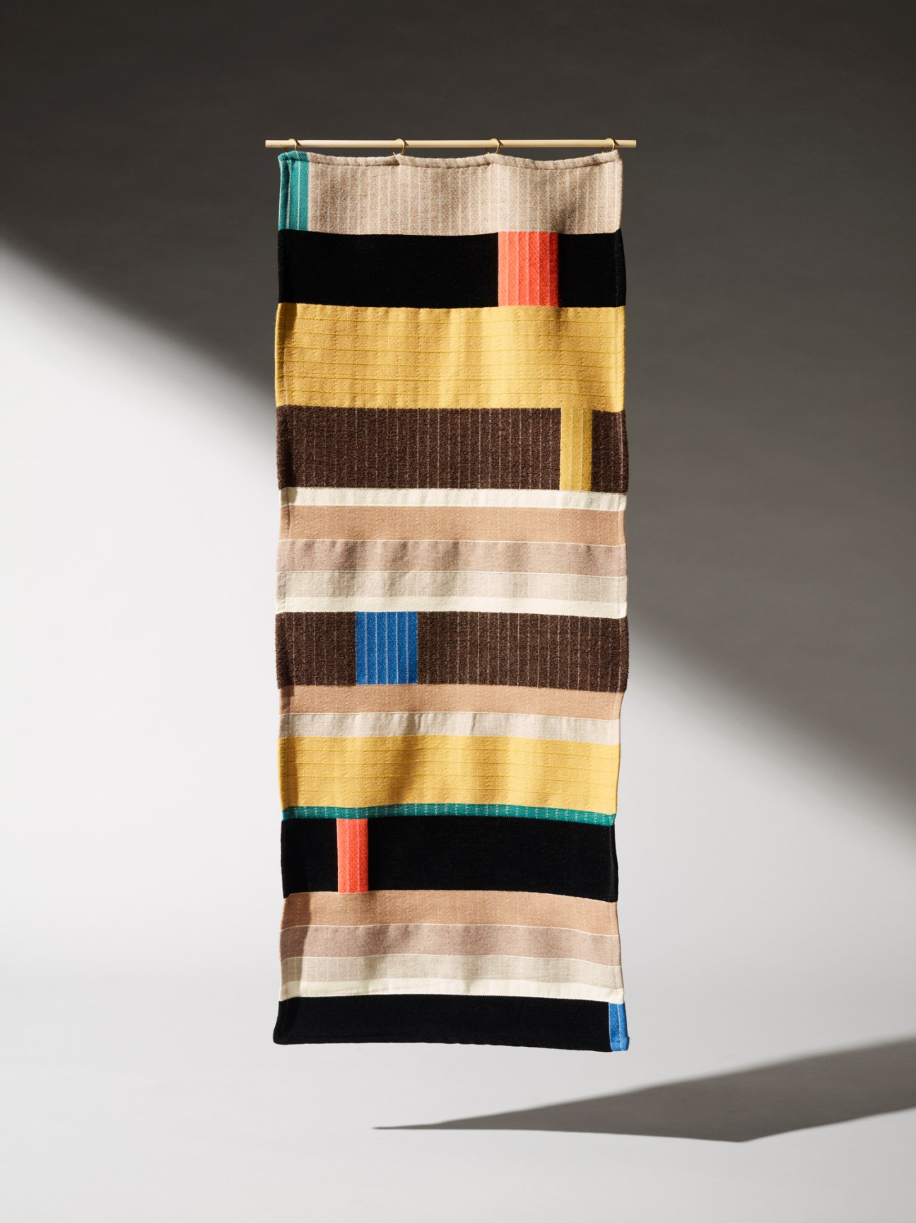 Anni Albers wall hanging with horizontal stripes in various colors including yellow, brown, black, and beige