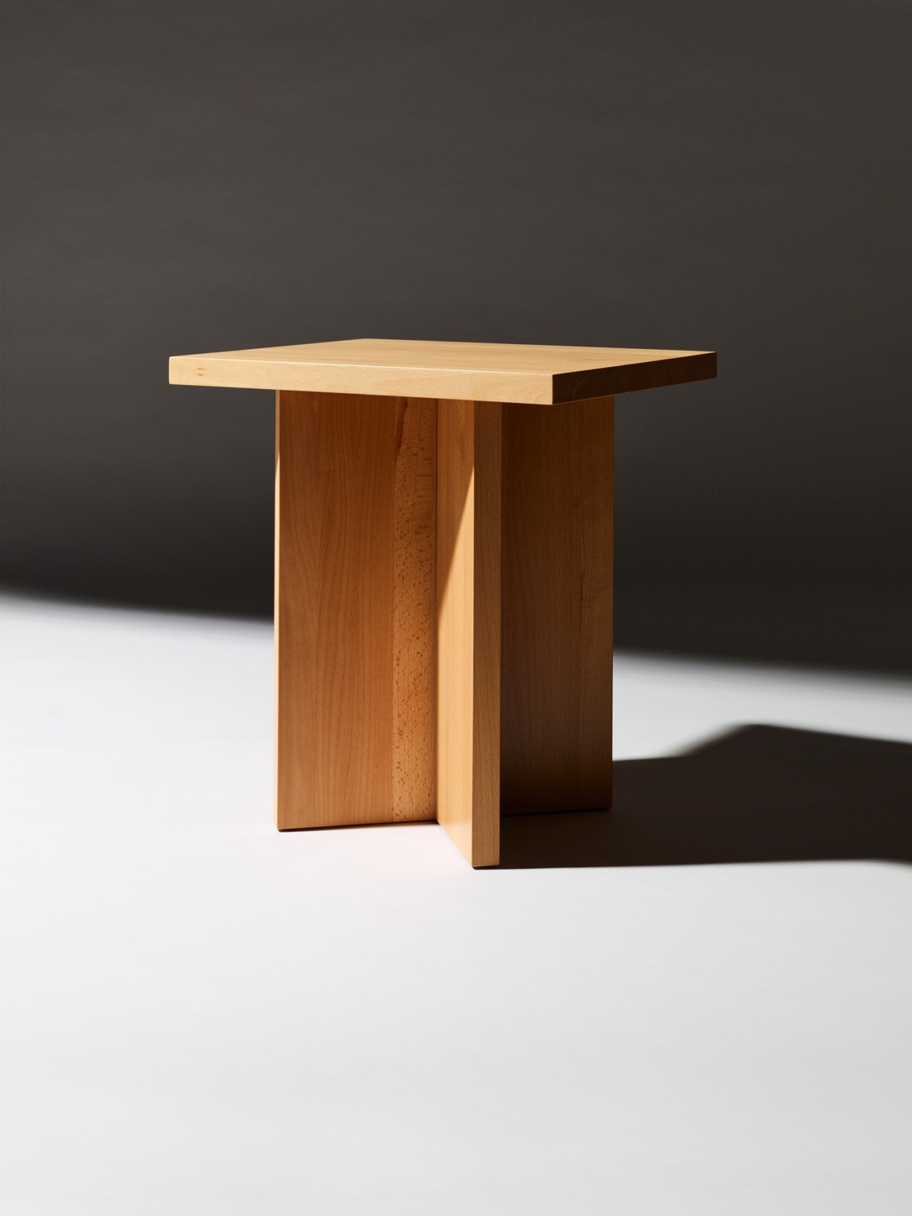 Corinth side table made from solid beech wood with cross-base design on white surface