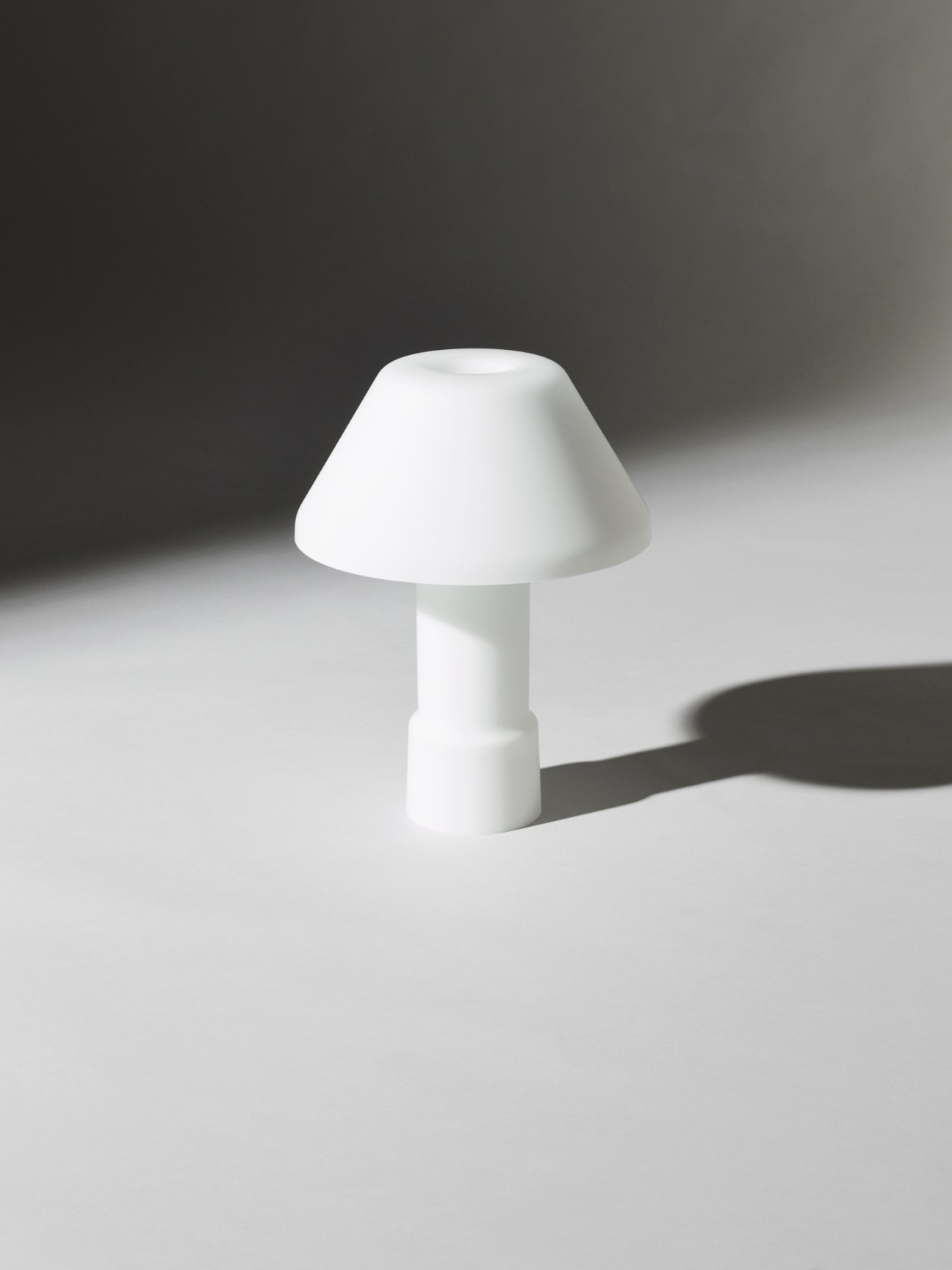 W163 Lampyre white opal glass lamp with mushroom-shaped shade and cylindrical base casting shadow