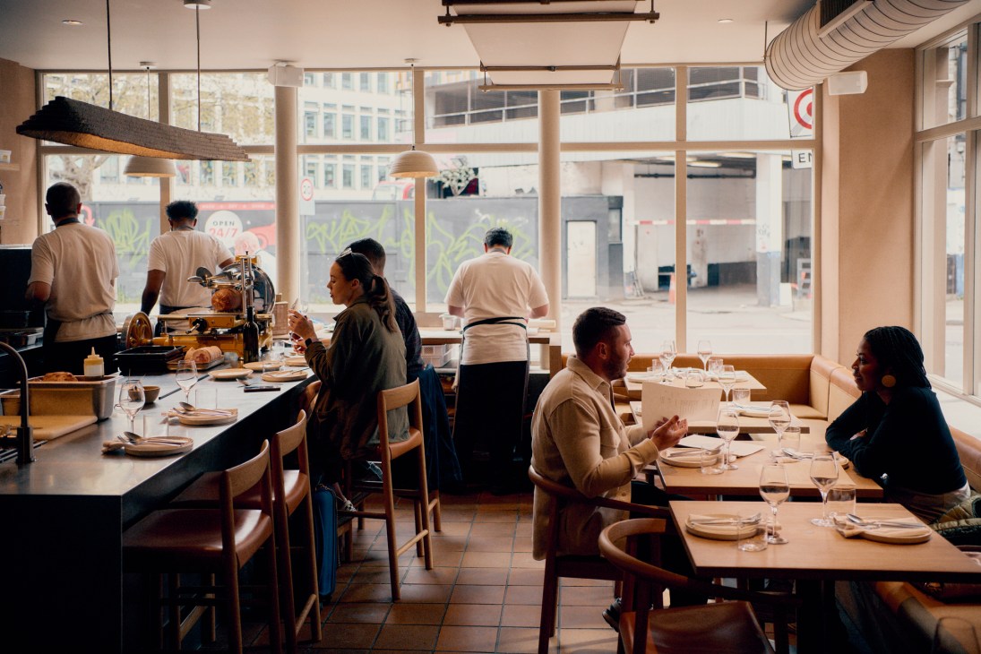 Interior of Manteca restaurant showing yellow walls and wood trim with diners seated