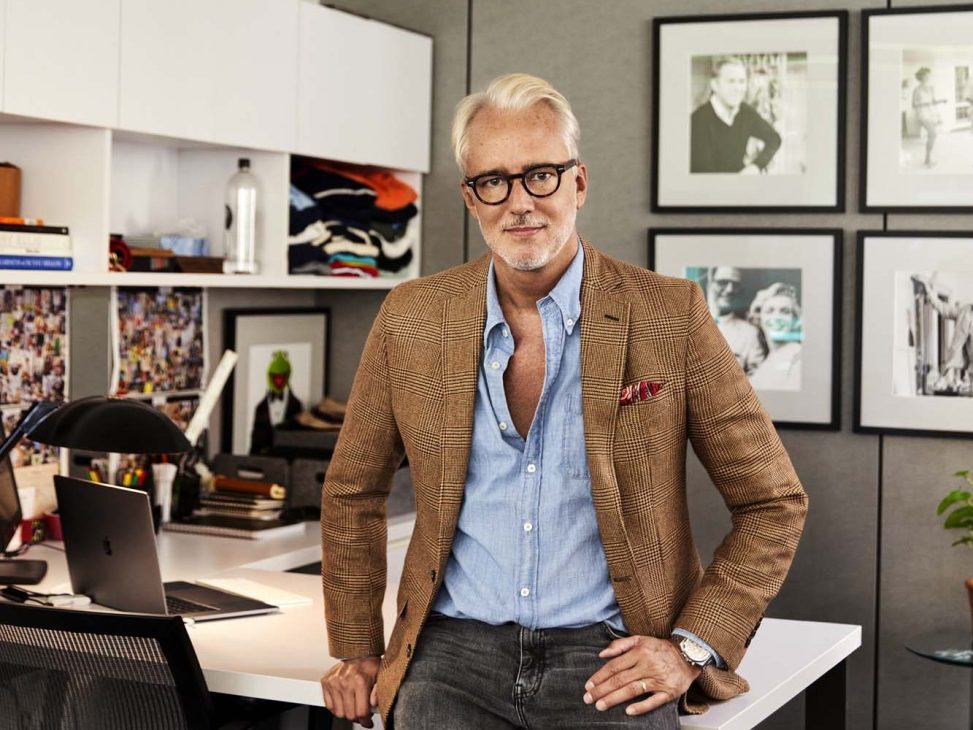 Michael Bastian, creative director of Brooks Brothers, standing in his workspace wearing a brown blazer and light blue shirt