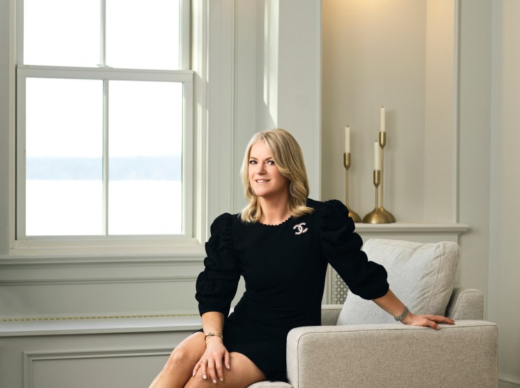 Pamela Mullinger sitting in a beige armchair wearing a black dress in an elegant white room