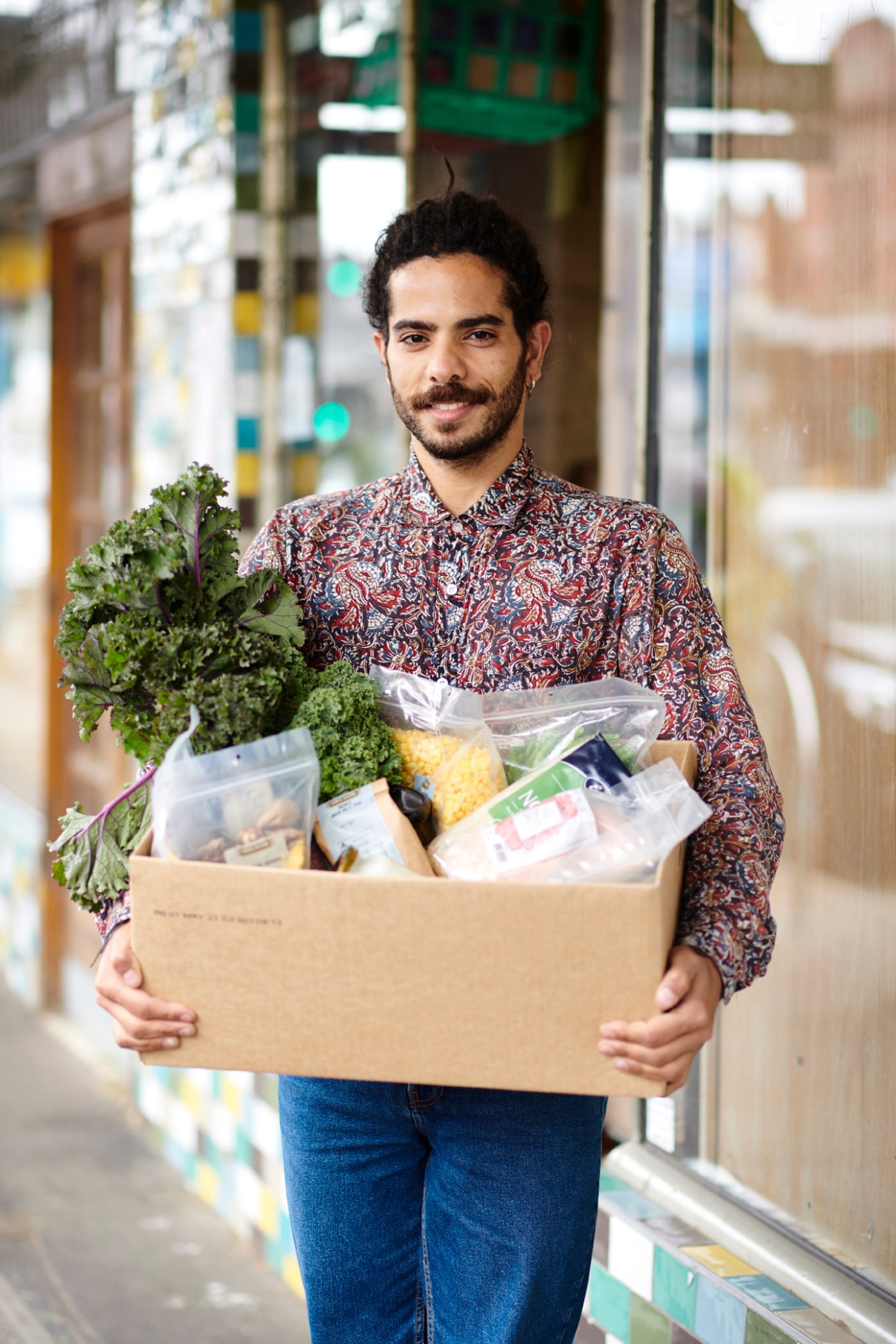 Man holding cardboard box of organic groceries on Melbourne high street