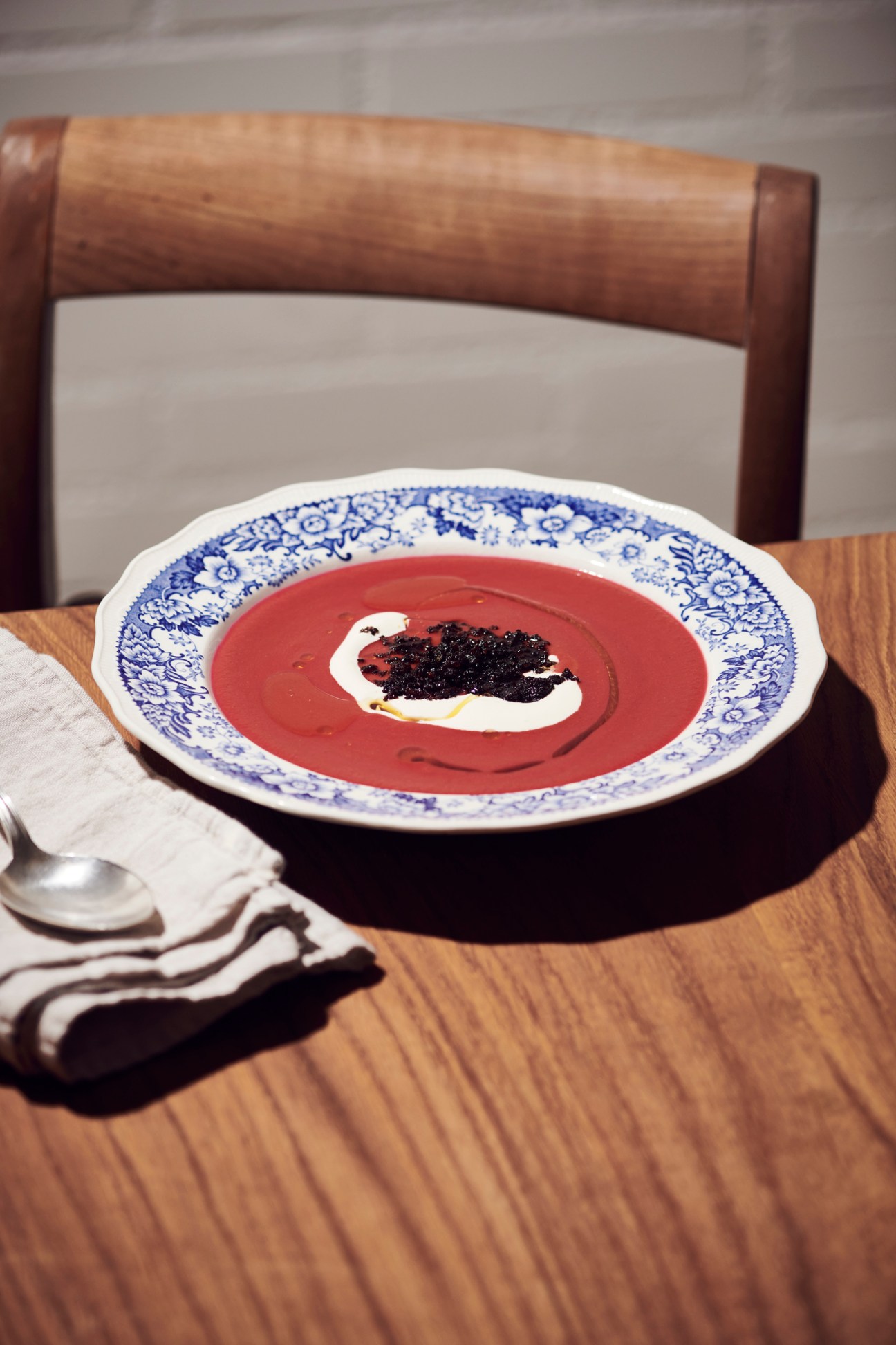 Bowl of deep red beetroot soup garnished with white sour cream and dark croutons