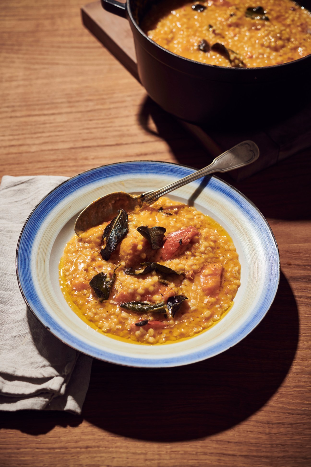 Creamy barley risotto topped with roasted orange pumpkin pieces in a blue-rimmed white bowl