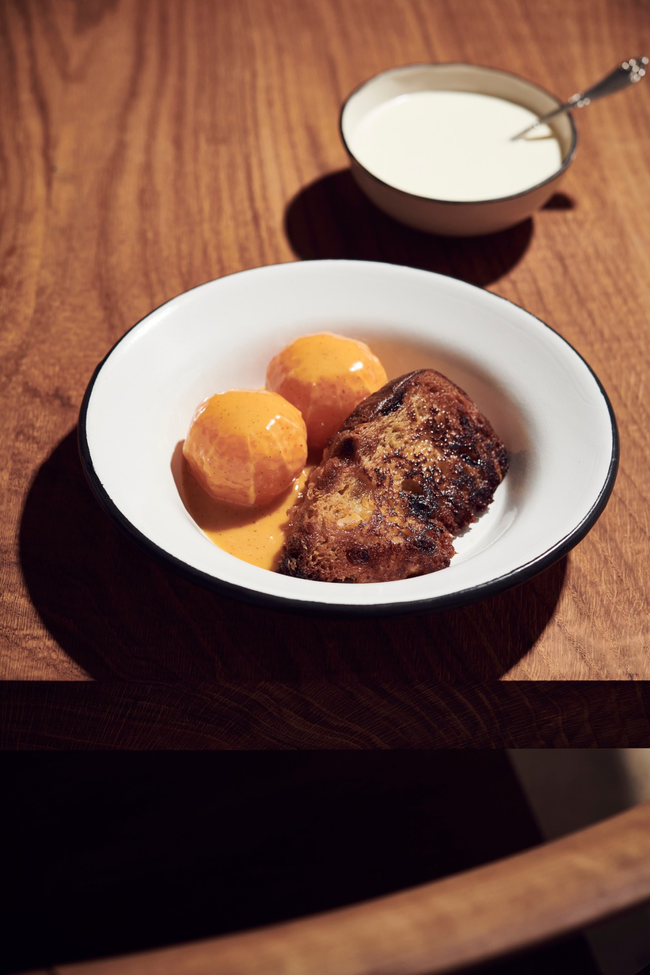 Panettone French toast with orange segments and persimmon sauce on white plate
