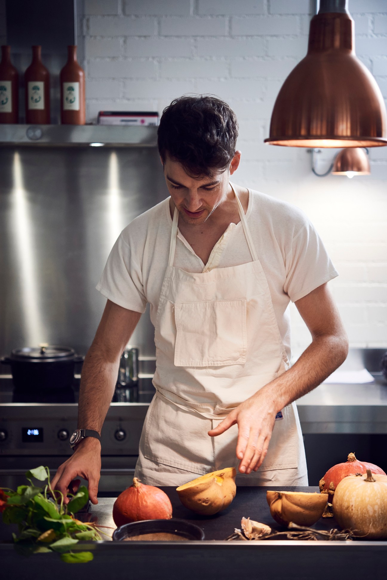 Chef Ralph Schelling in white apron preparing seasonal vegetables including pumpkins in a modern kitchen