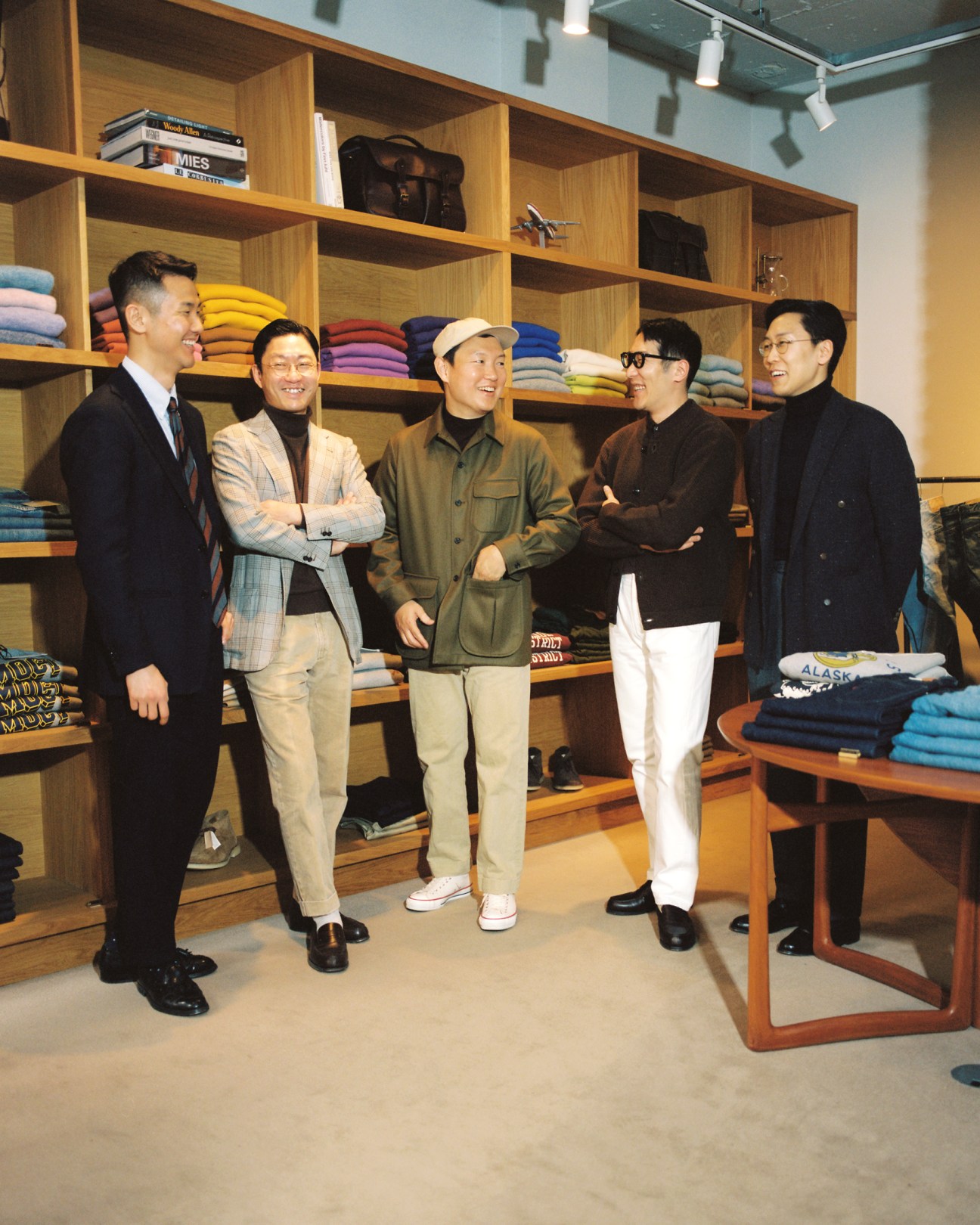 Five men standing and conversing in Random Walk boutique interior with wooden shelving displaying colorful clothing