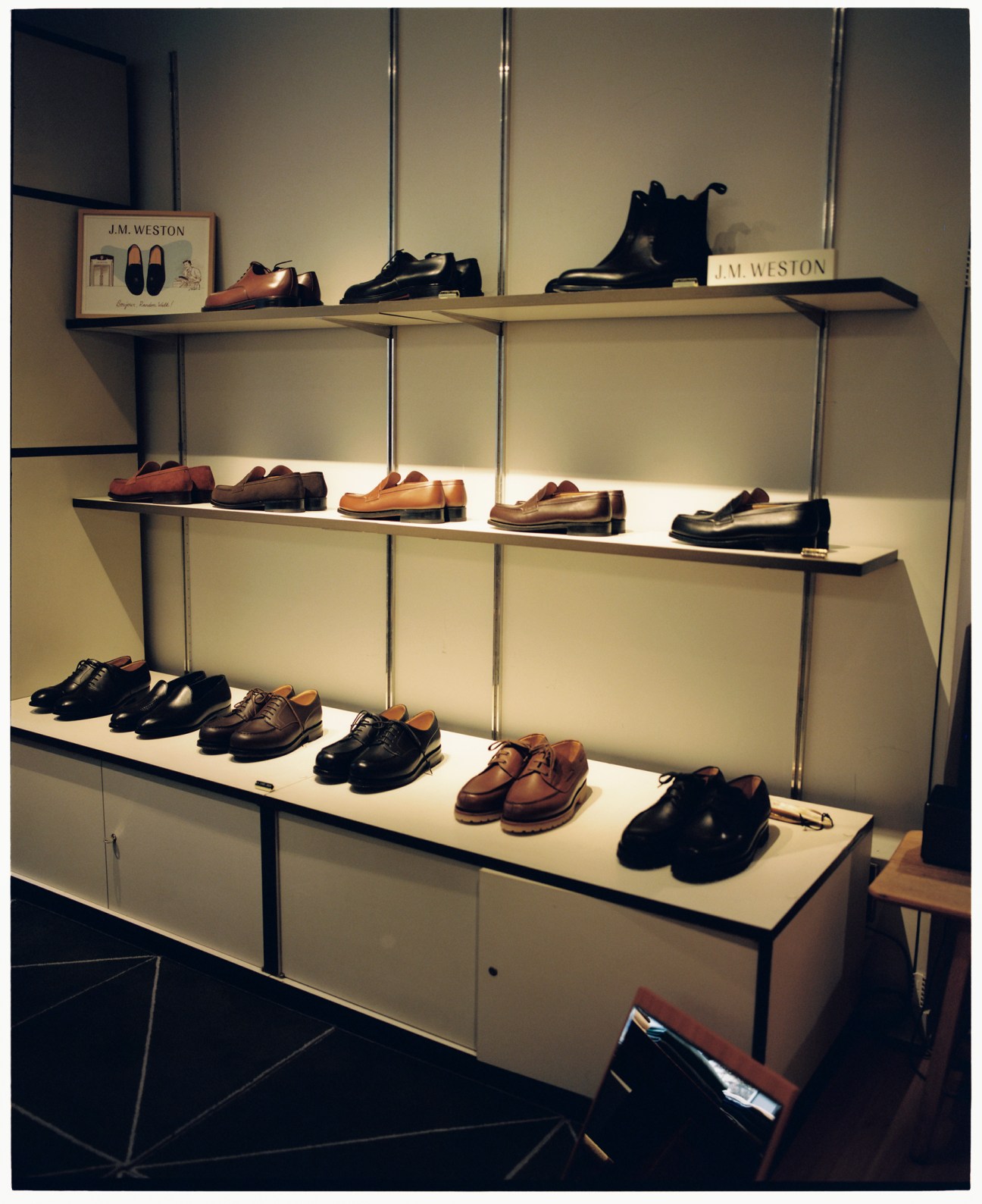 Display of leather shoes on white shelves with J.M. Weston branding visible
