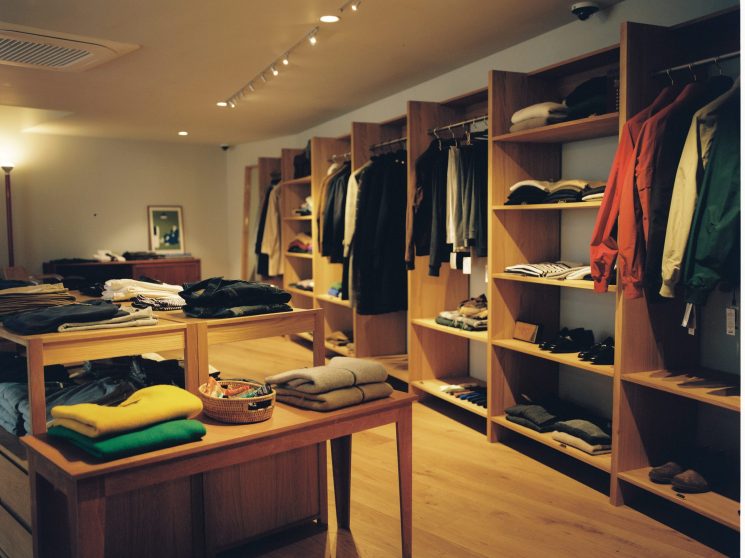 Interior of Random Walk boutique showing wooden shelving units displaying folded clothing and hanging garments