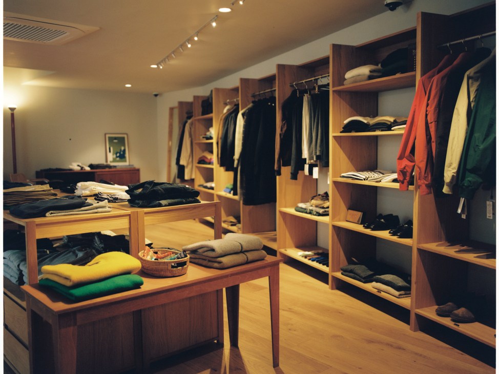 Interior of Random Walk boutique showing wooden shelving units displaying folded clothing and hanging garments