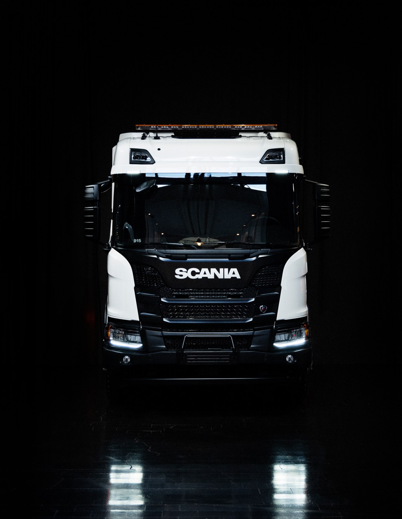White and black Scania truck cab photographed against dark background