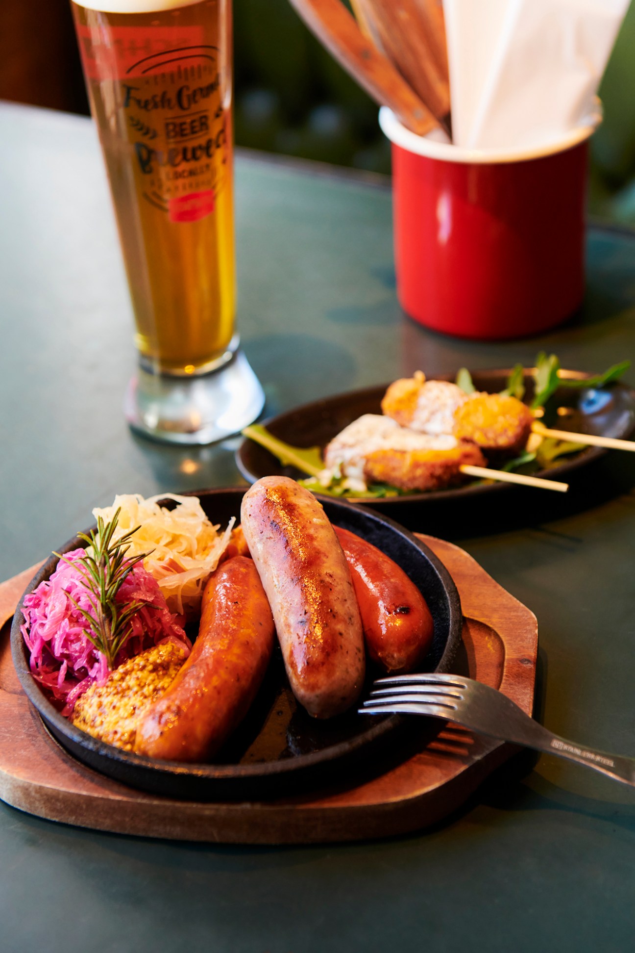 Grilled German sausages served on a black cast iron plate with sauerkraut, corn and accompaniments