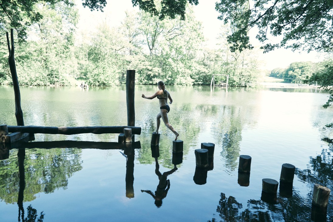 A child balances on wooden stepping stones across a lake in the Amsterdam Forest.