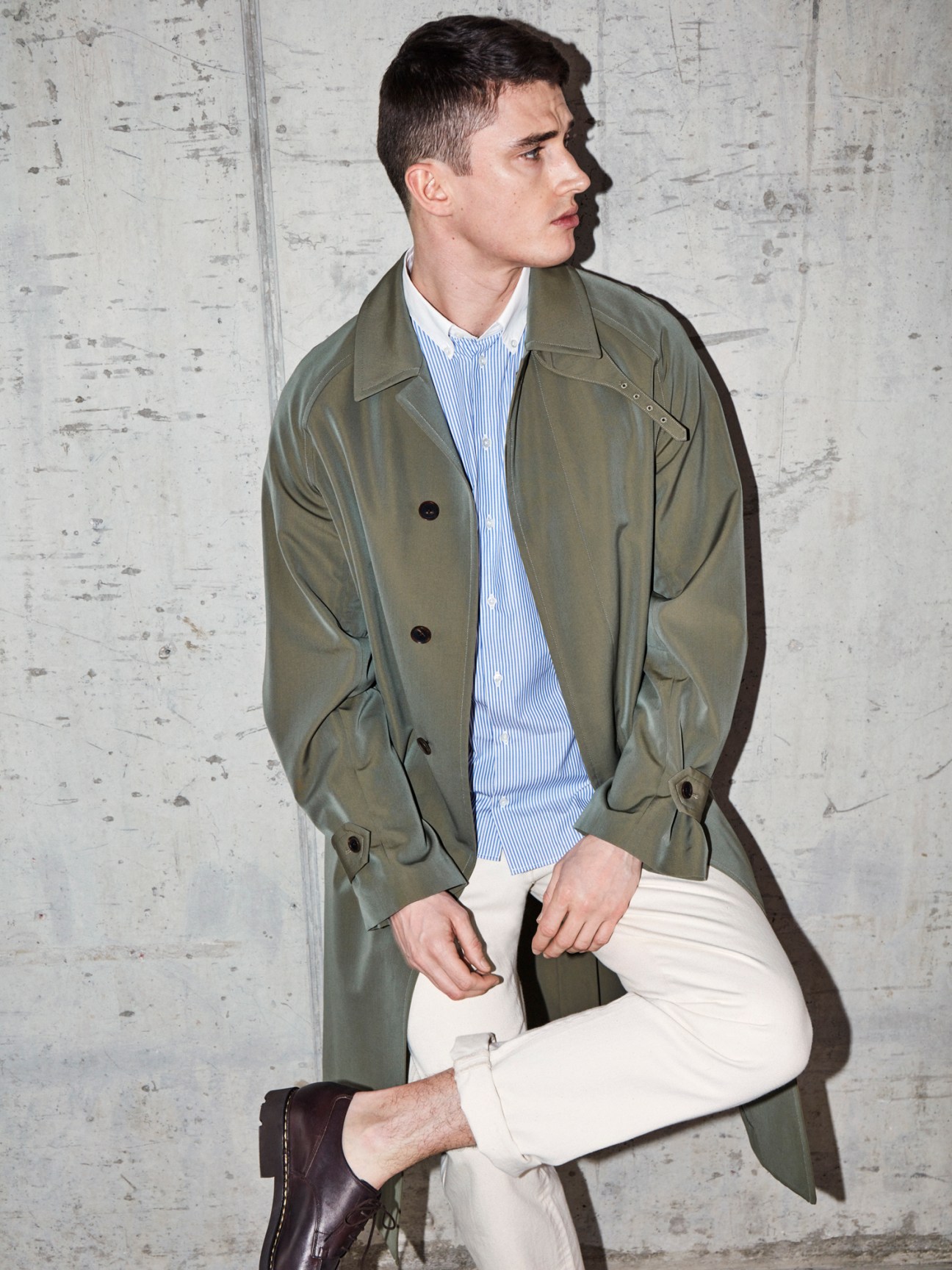 Man in olive coat by Auralee, striped shirt by Mackintosh, jeans by APC and shoes by Paraboot