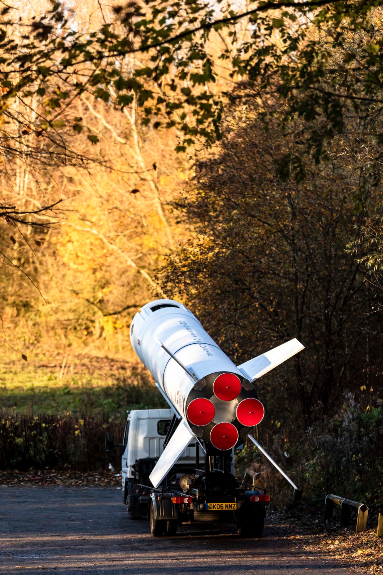 White and red rocket mounted on flatbed truck bed in industrial area.
