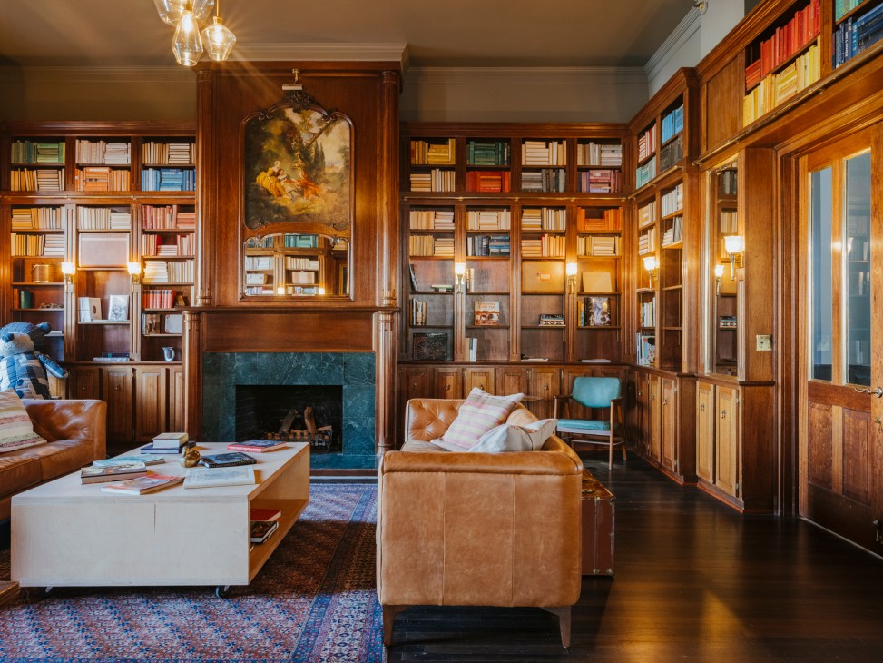 Elegant wood-paneled library with built-in bookshelves, leather seating, fireplace and warm lighting