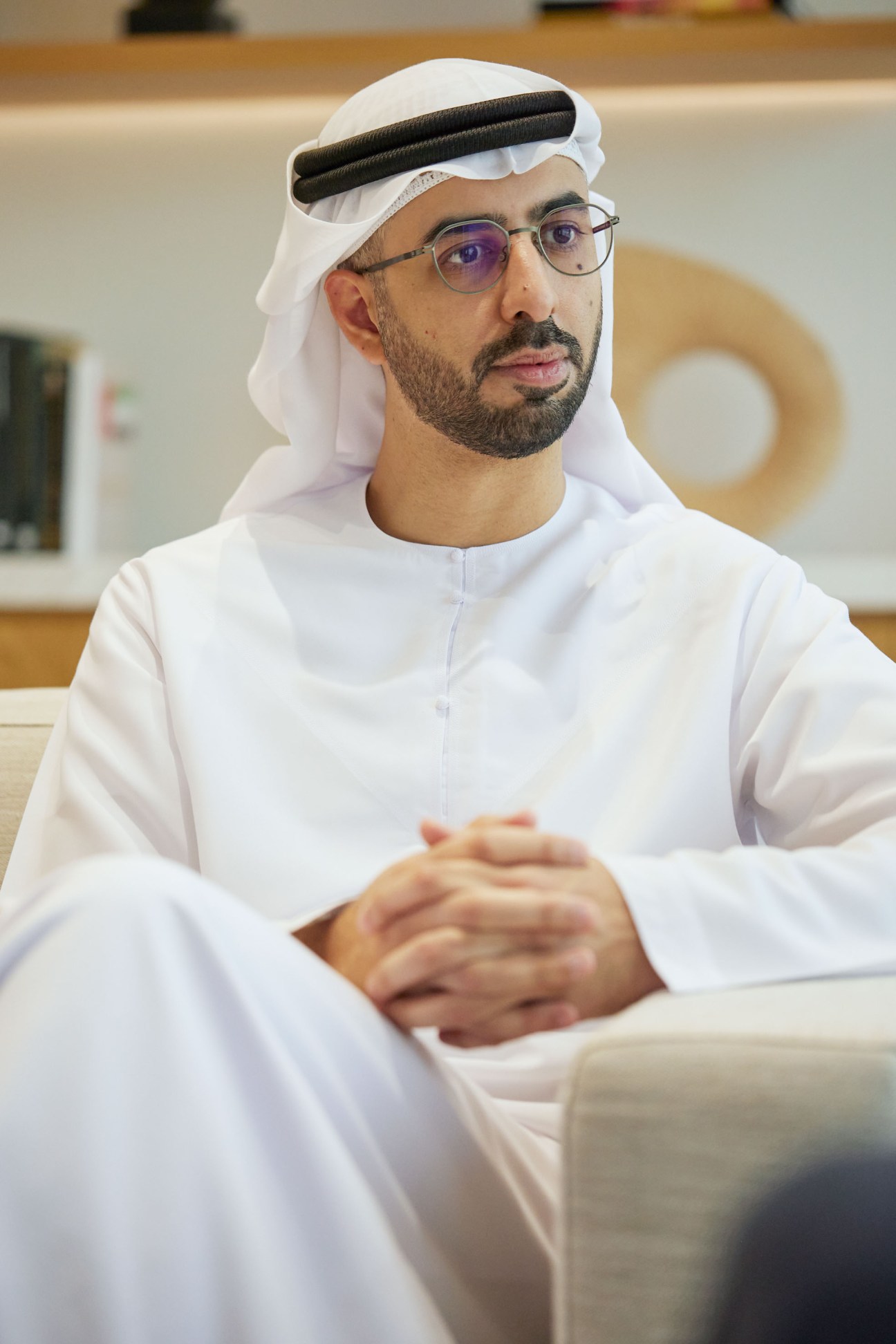 Omar Sultan Al Olama, UAE Minister of State for Artificial Intelligence, in traditional white kandura and ghutra, sitting at a desk with a laptop.