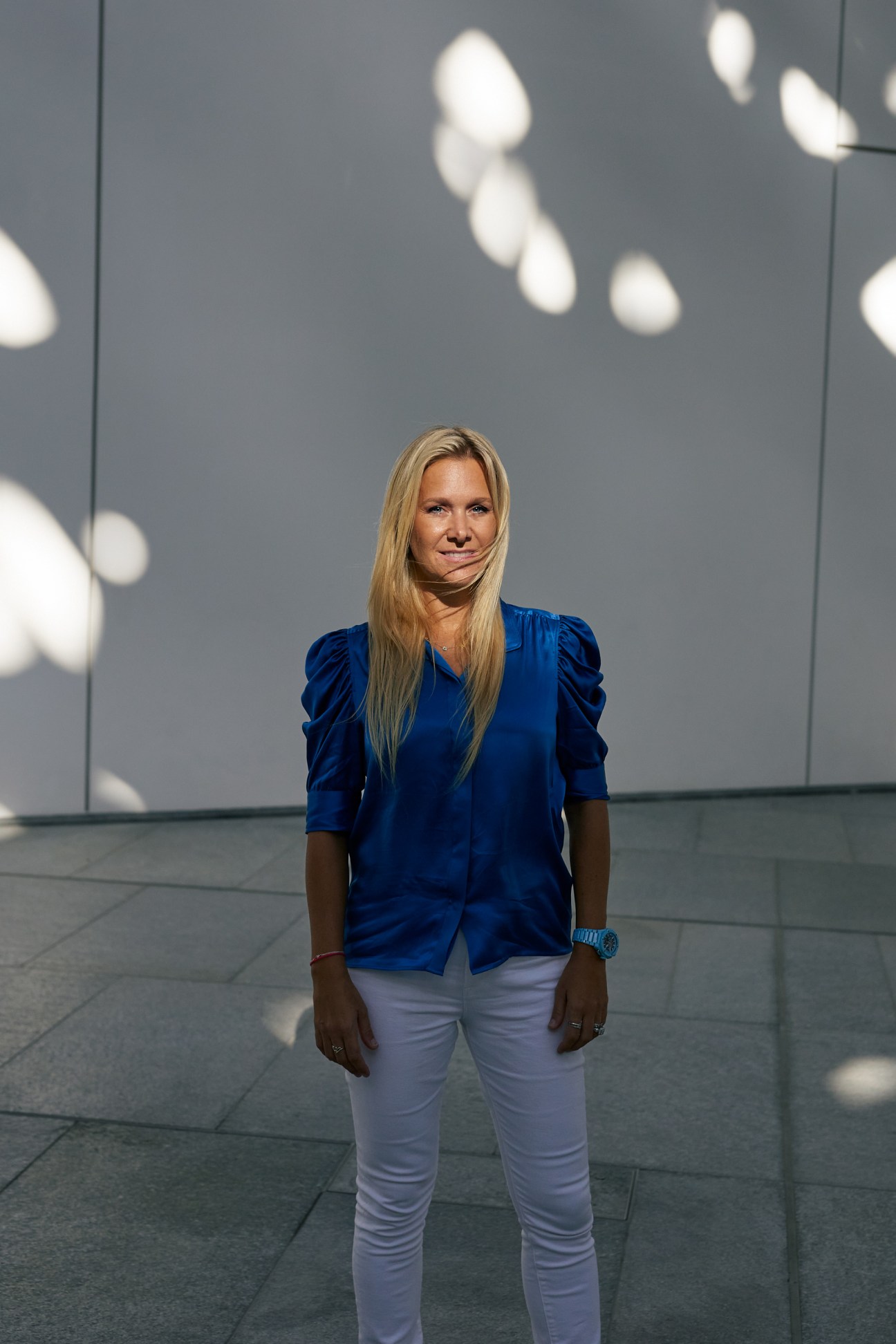 Nancy Paton, founder of Desert Rose Films, poses for a portrait against a gray wall with bokeh lighting.