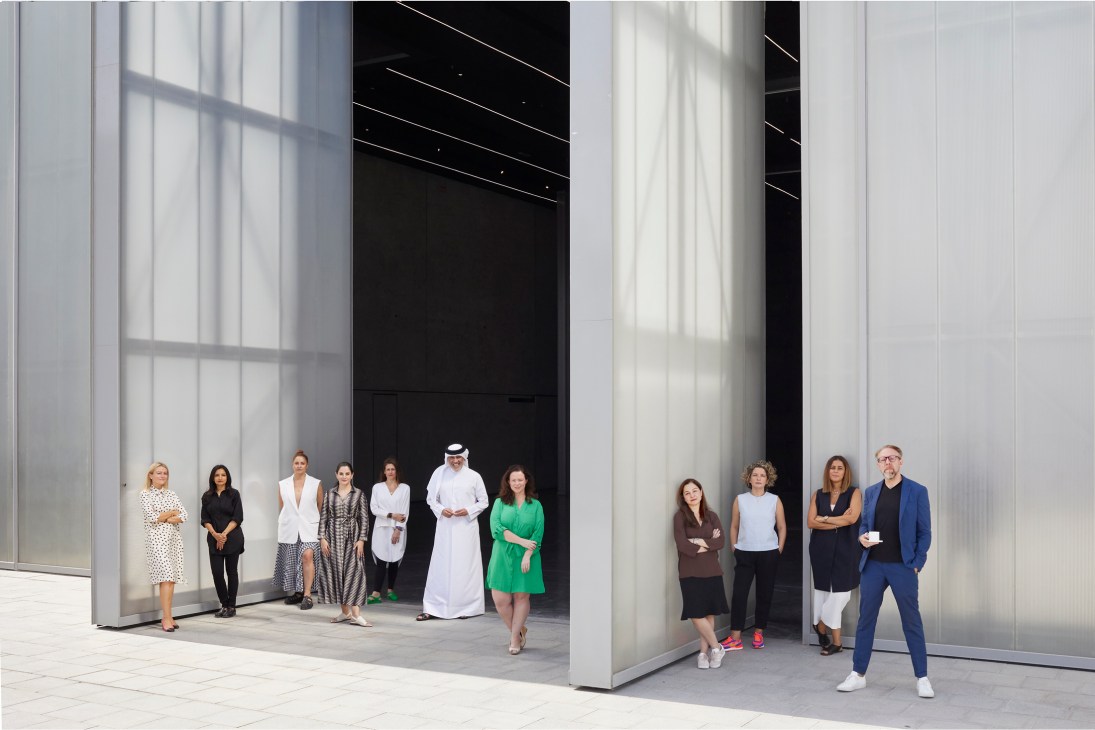 The Alserkal Initiatives team poses in front of minimalist white architecture at Concrete warehouse in Dubai's Alserkal Avenue.