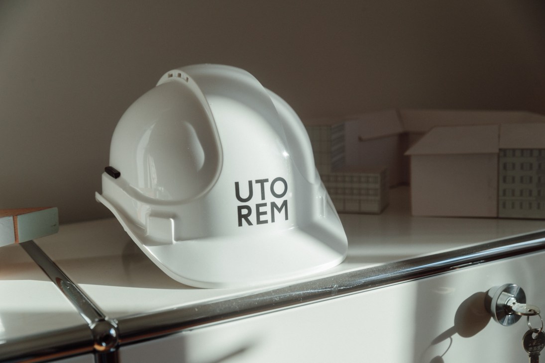 White hard hat with UTOREM logo on construction site or development project