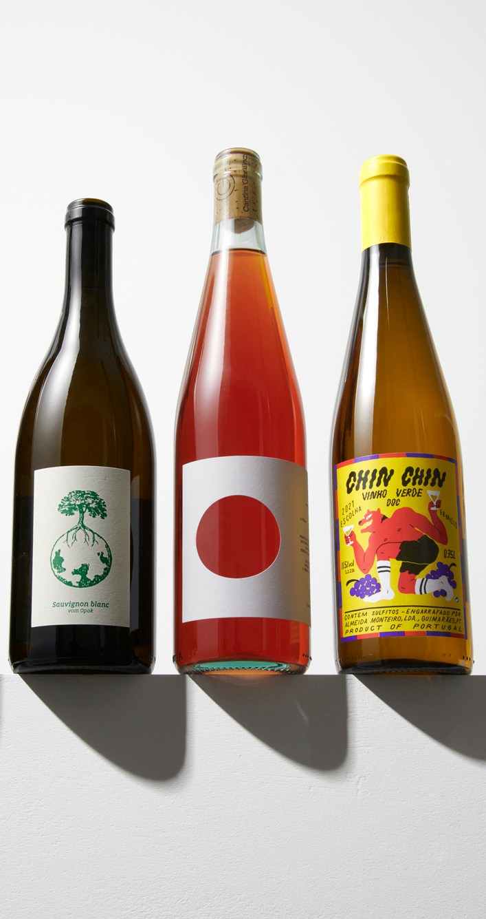 Three wine bottles with distinctive label designs - minimalist tree logo, simple red circle, and colorful cartoon graphics