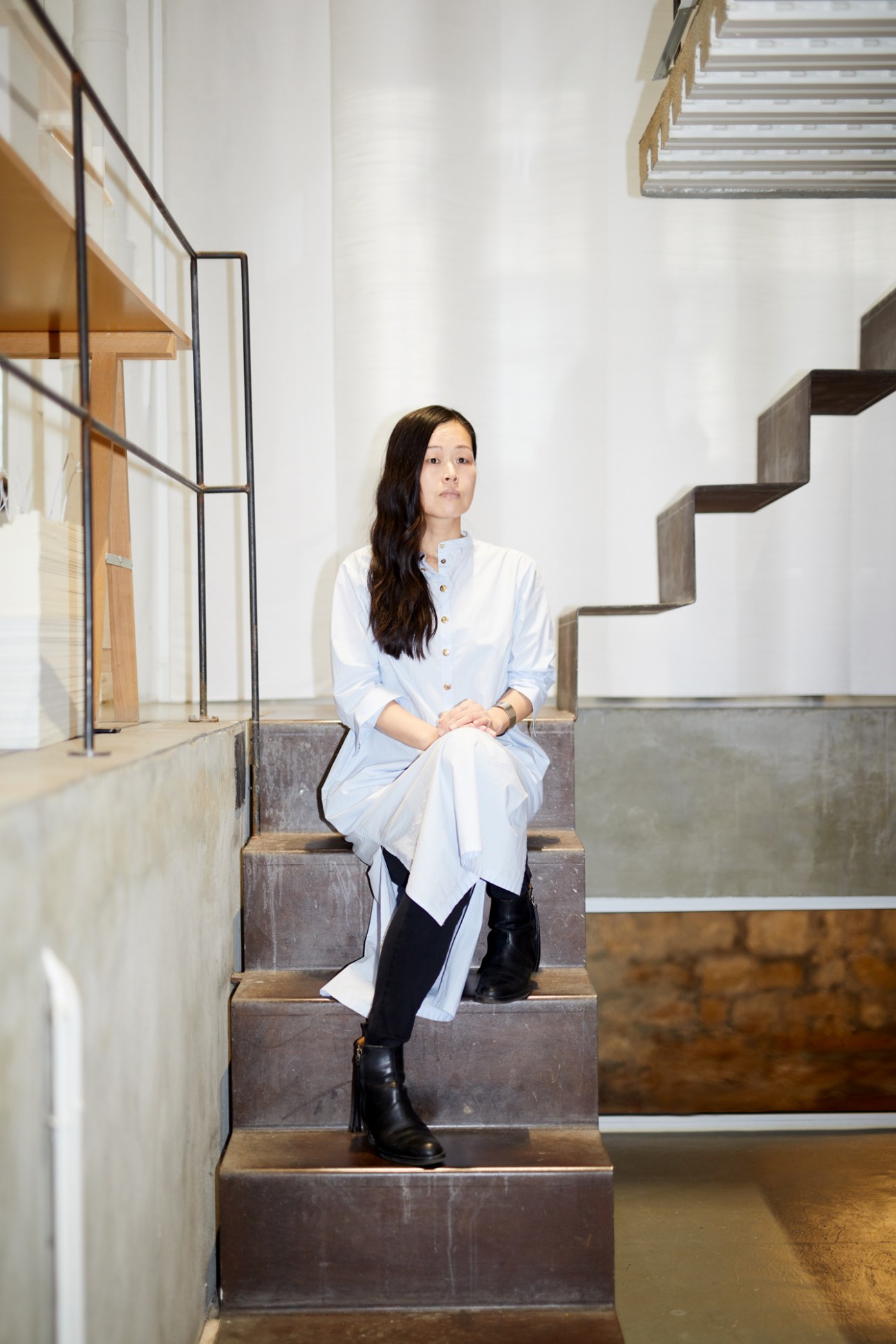 Yuki Ikeguchi sitting on modern concrete stairs in contemporary architectural interior