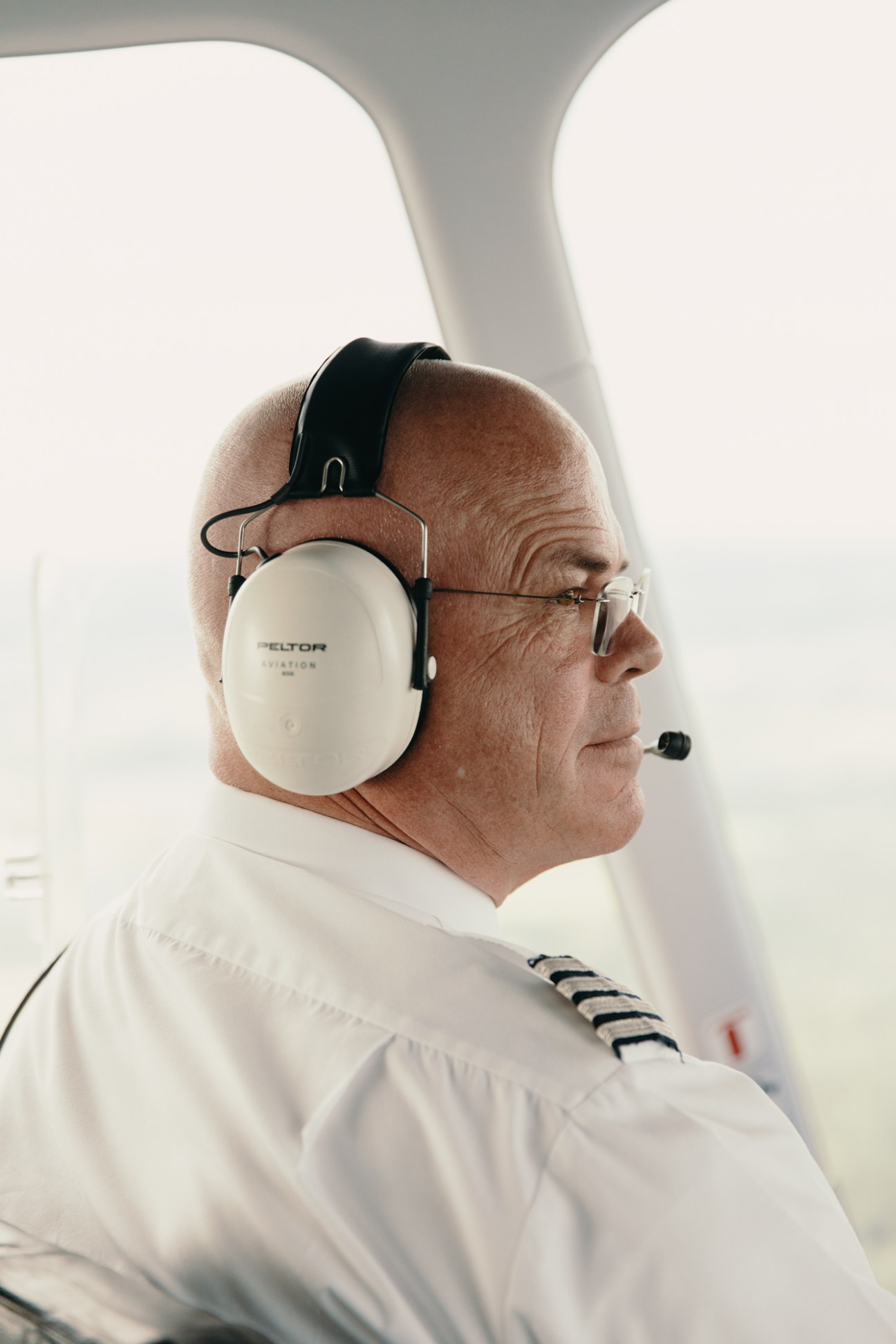 Captain Fritz Günther in Zeppelin cockpit wearing headphones and white pilot uniform with epaulettes