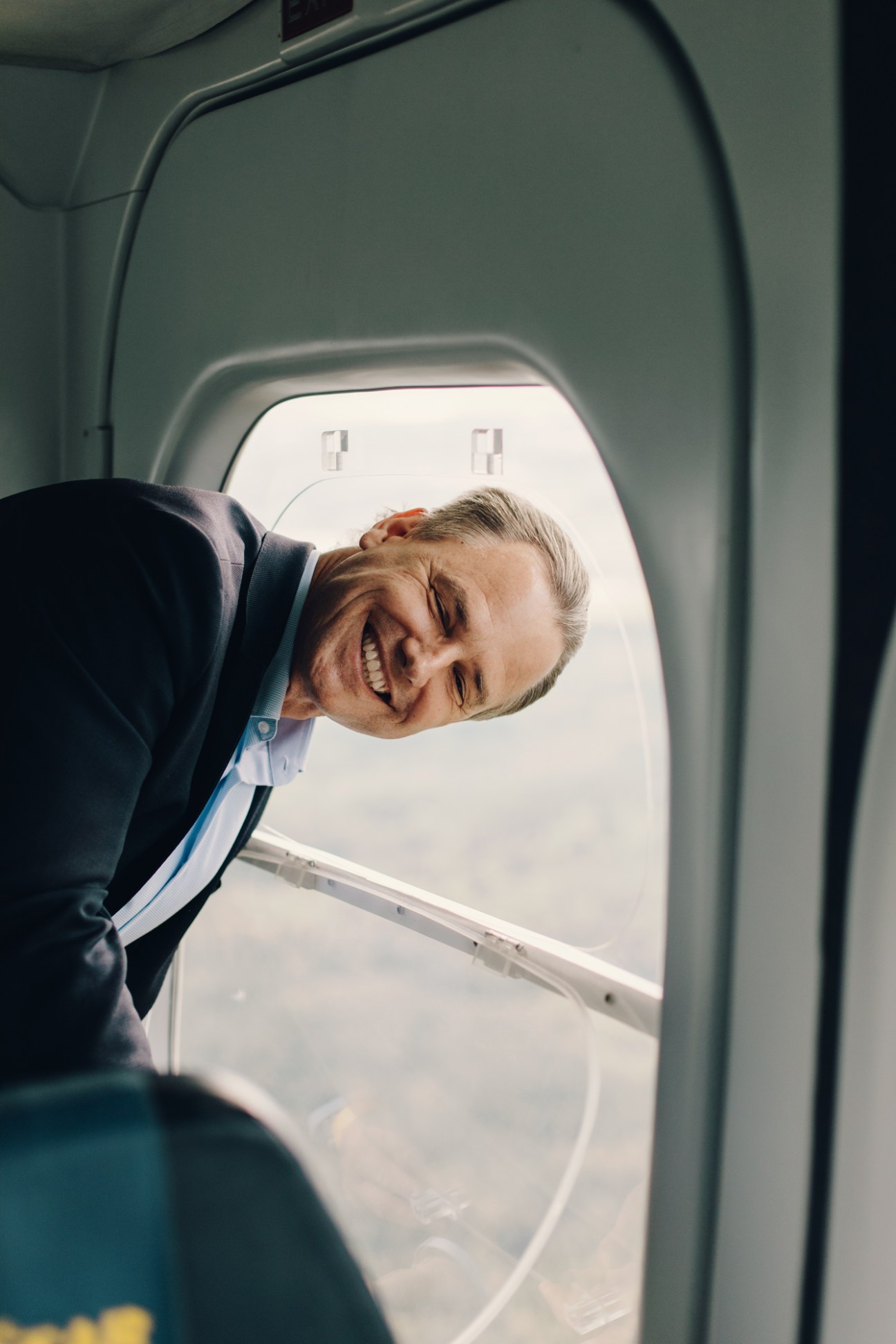 Eckhard Breuer, CEO of ZLT Zeppelin, smiling while looking out airplane window wearing dark suit