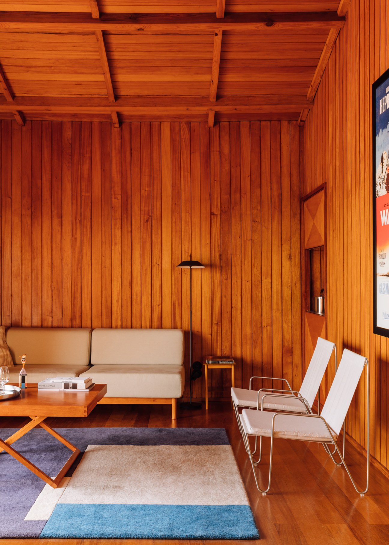 Interior living room showing modern furniture including Verner Panton Bachelor chairs and custom beige sofa with wooden walls