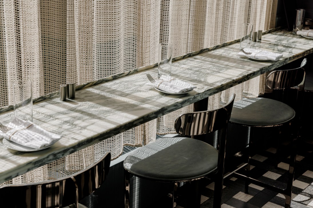Restaurant dining area with marble counter, bar stools and woven curtains