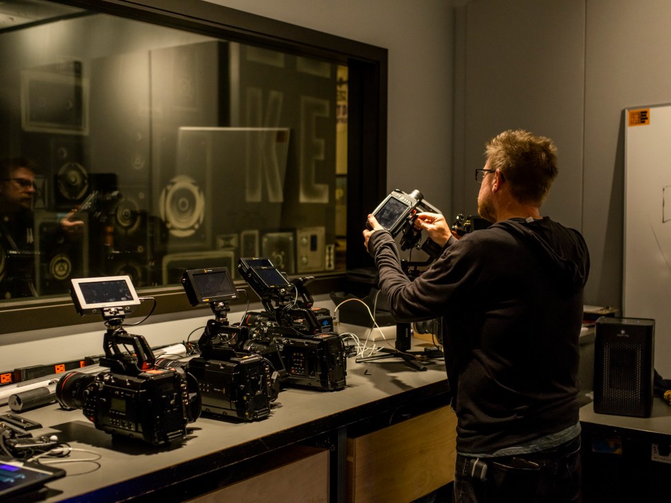 Jim Beckmann examines professional video cameras and equipment on a workbench in a modern media facility