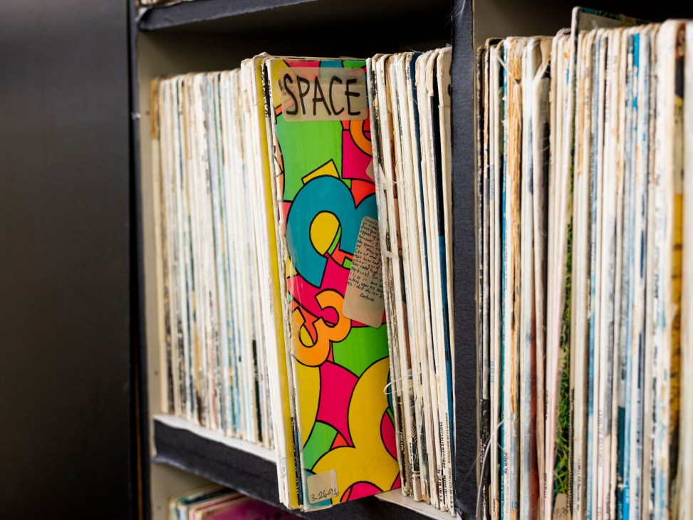 Colorful vinyl records organized on shelves in a media office, with one record prominently displaying 'SPACE' text