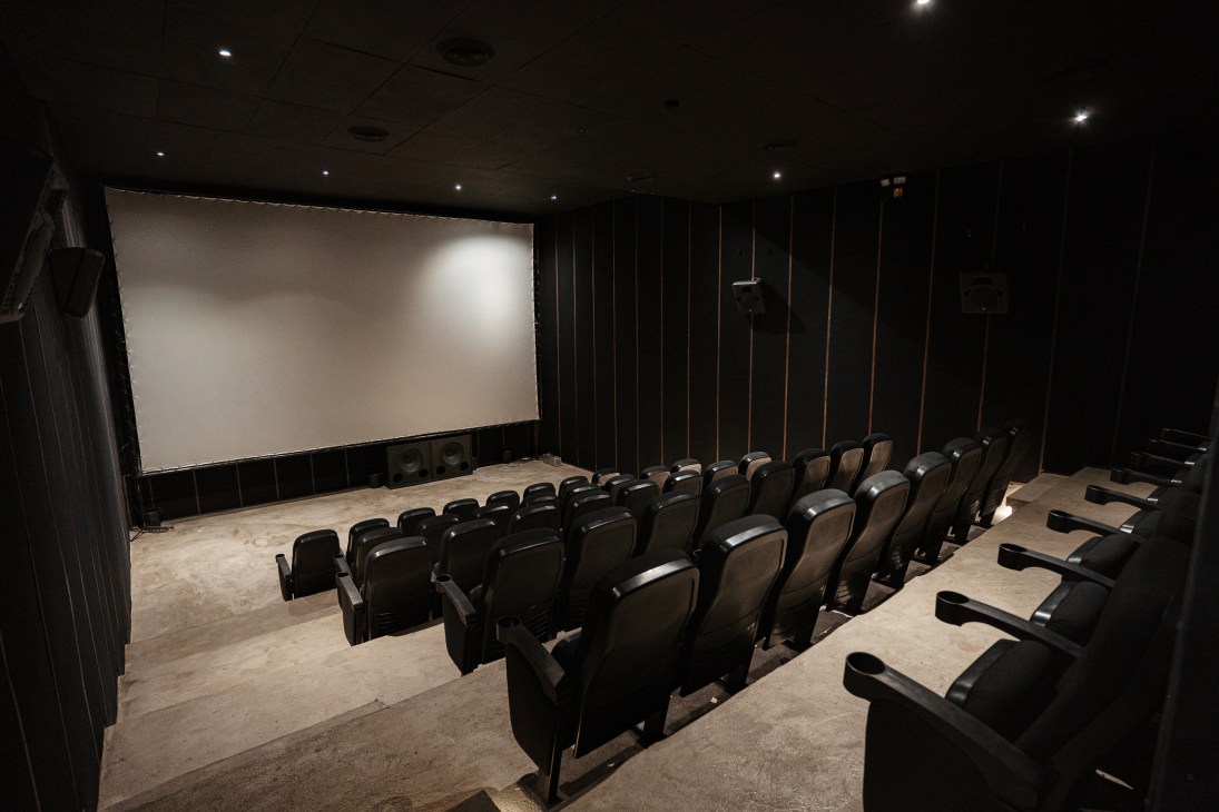 Interior view of Sine Pop's minimalist 48-seat cinema screening room with dark walls and leather recliners