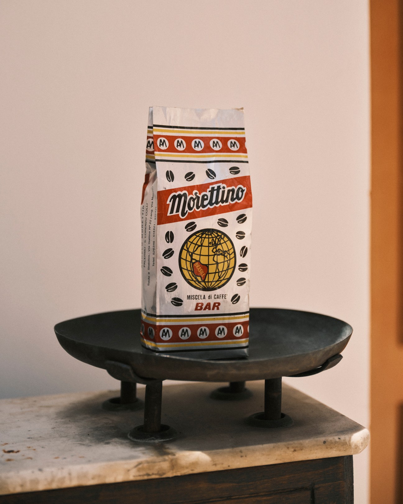 Vintage Morettino coffee package with globe logo sits on dark ceramic plate on wooden surface