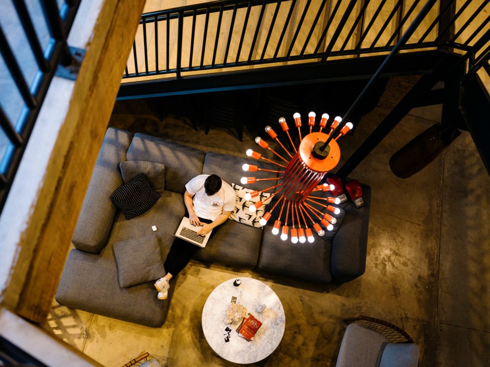 Dialexa employee working on laptop in modern office with distinctive spiral chandelier overhead