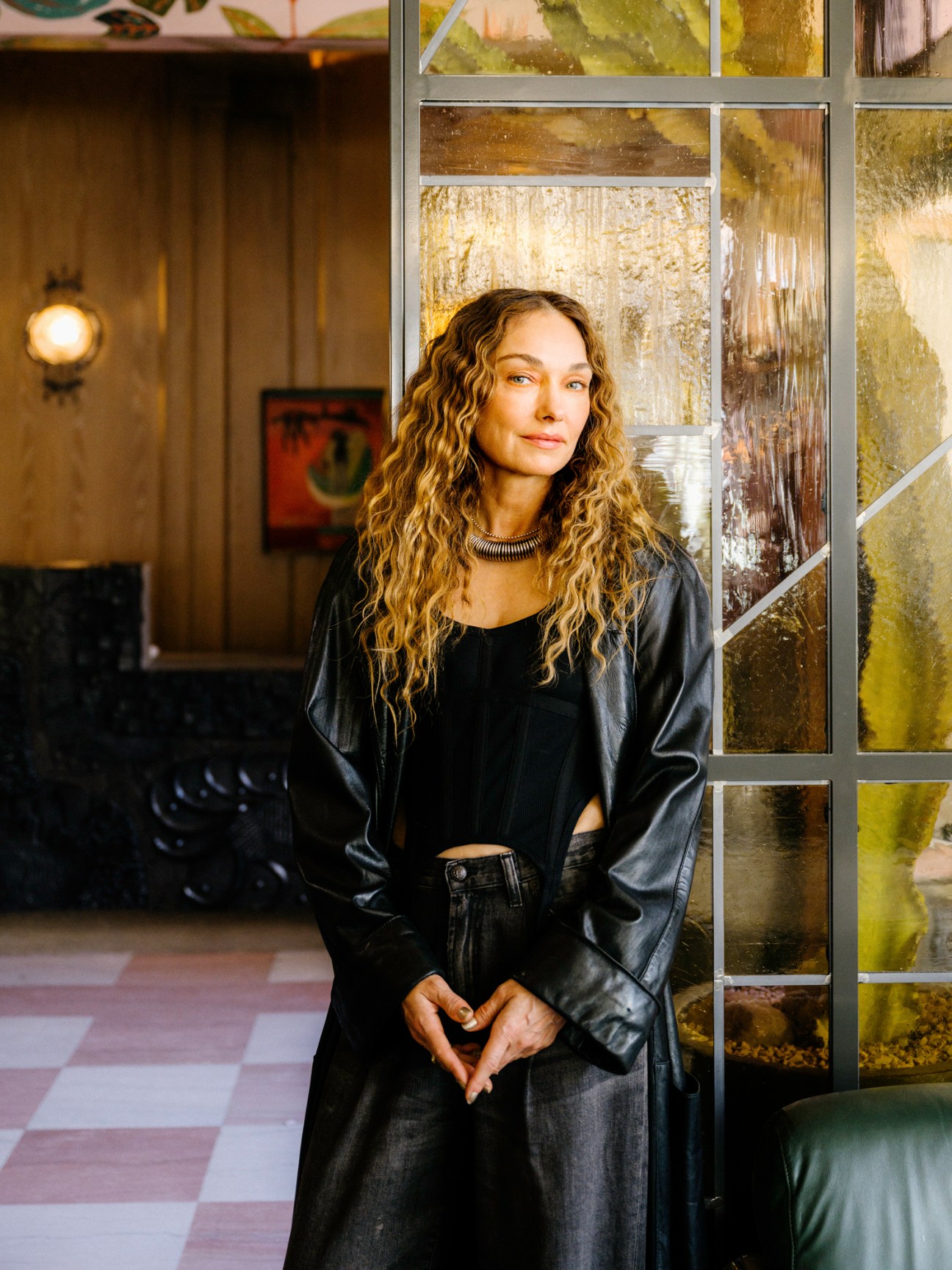 Designer Kelly Wearstler standing in hotel interior with decorative glass panels and modern furnishings