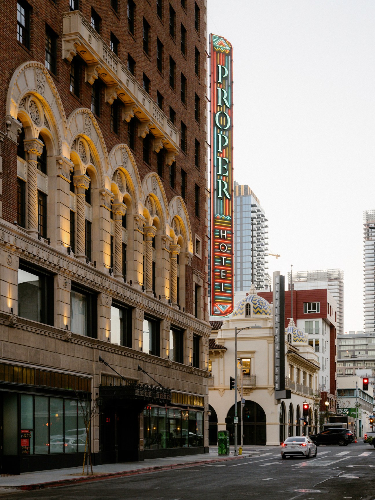 Exterior view of Downtown LA Proper hotel building with illuminated vertical signage and historic architecture