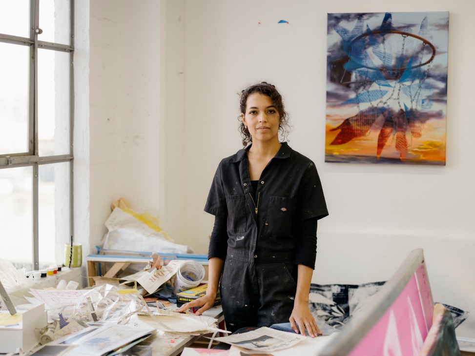 Artist Jessica Taylor Bellamy standing in her studio workspace surrounded by paintings and art materials