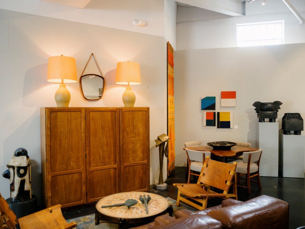 Mid-century modern furniture showroom interior with wooden cabinet, table lamps, dining set and artwork