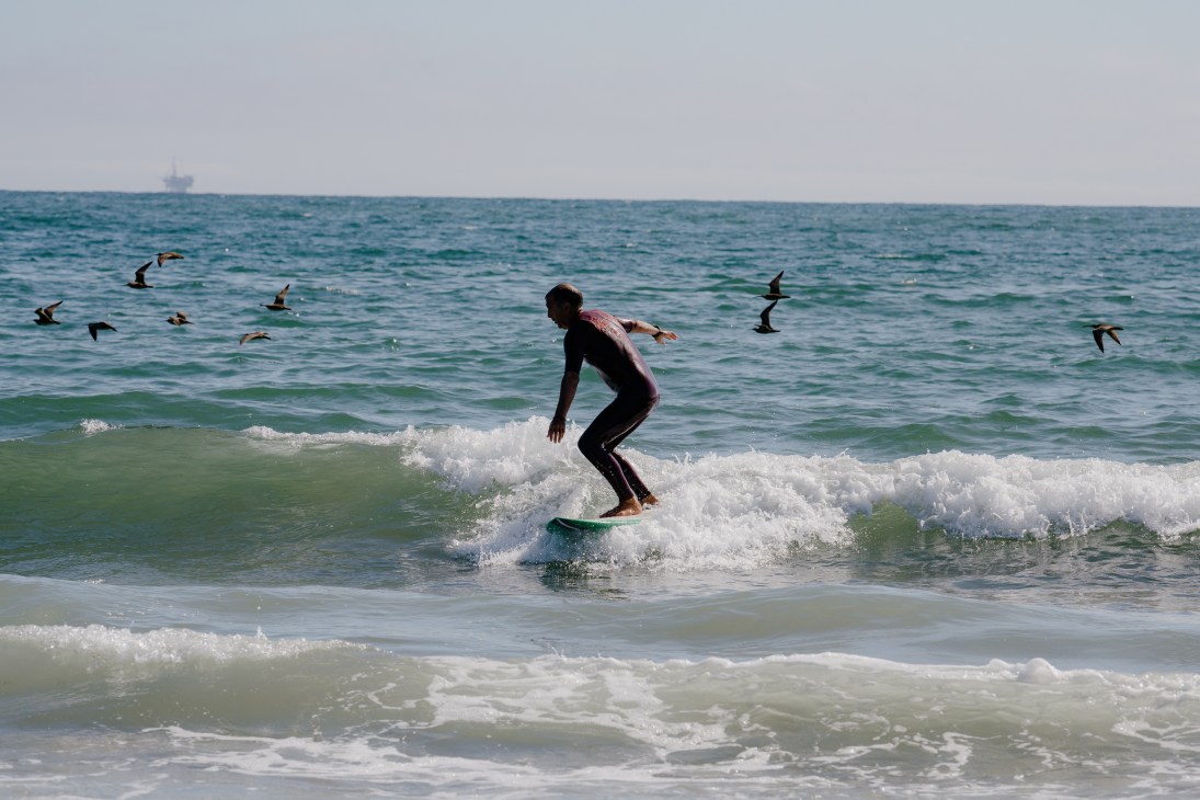 Adult student catching wave during surfing lesson in California