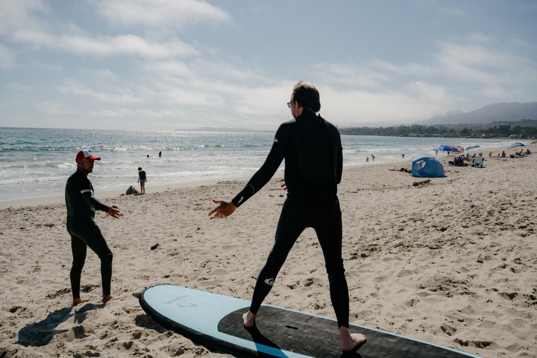 Surfing instructor demonstrating technique on beach before ocean practice