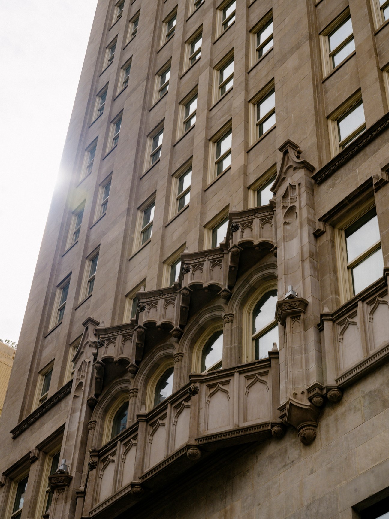 Stone building facade with ornate Gothic Revival arches and columns on lower floors