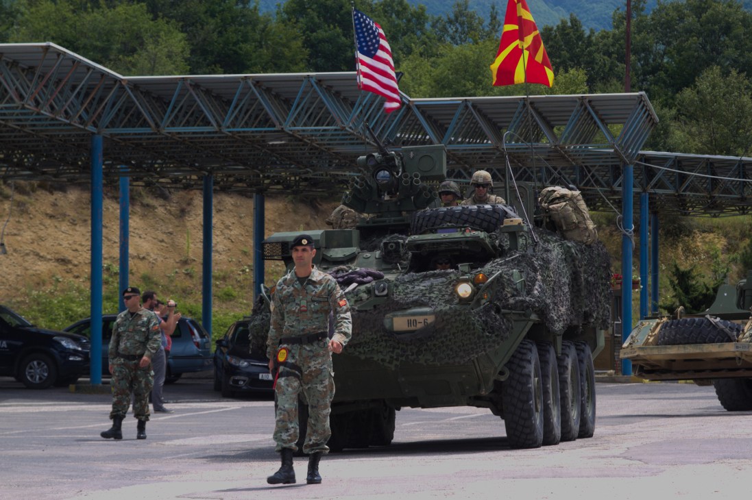 Military armored vehicle with soldiers and American and Macedonian flags during NATO exercise