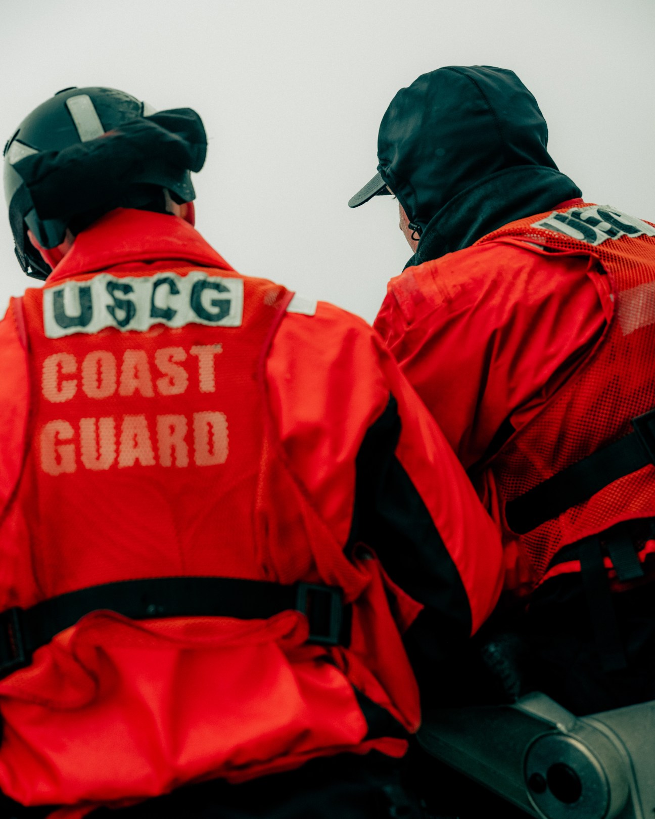 Two Coast Guard personnel in bright red jackets and dark caps conducting water rescue training exercise