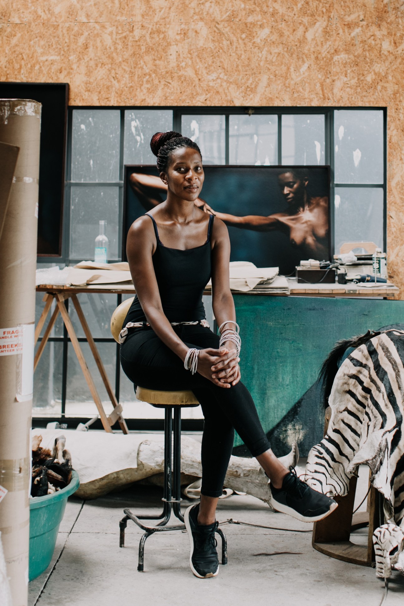 Artist Nandipha Mntambo sitting in her Johannesburg studio workspace with art supplies and materials