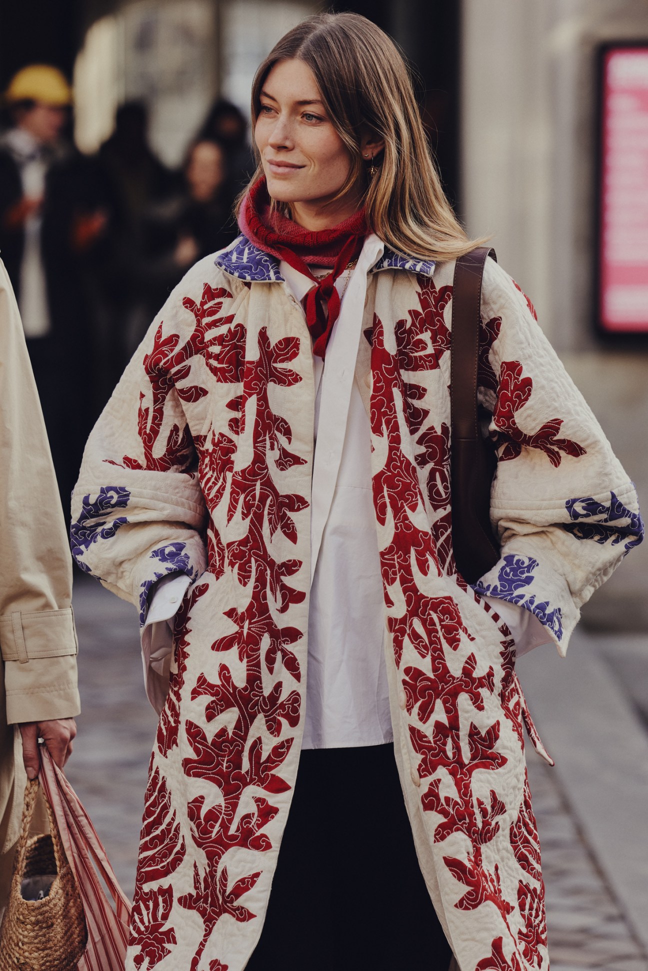 Person in stylish dark coat and wide-brimmed hat walking on Copenhagen street during fashion week