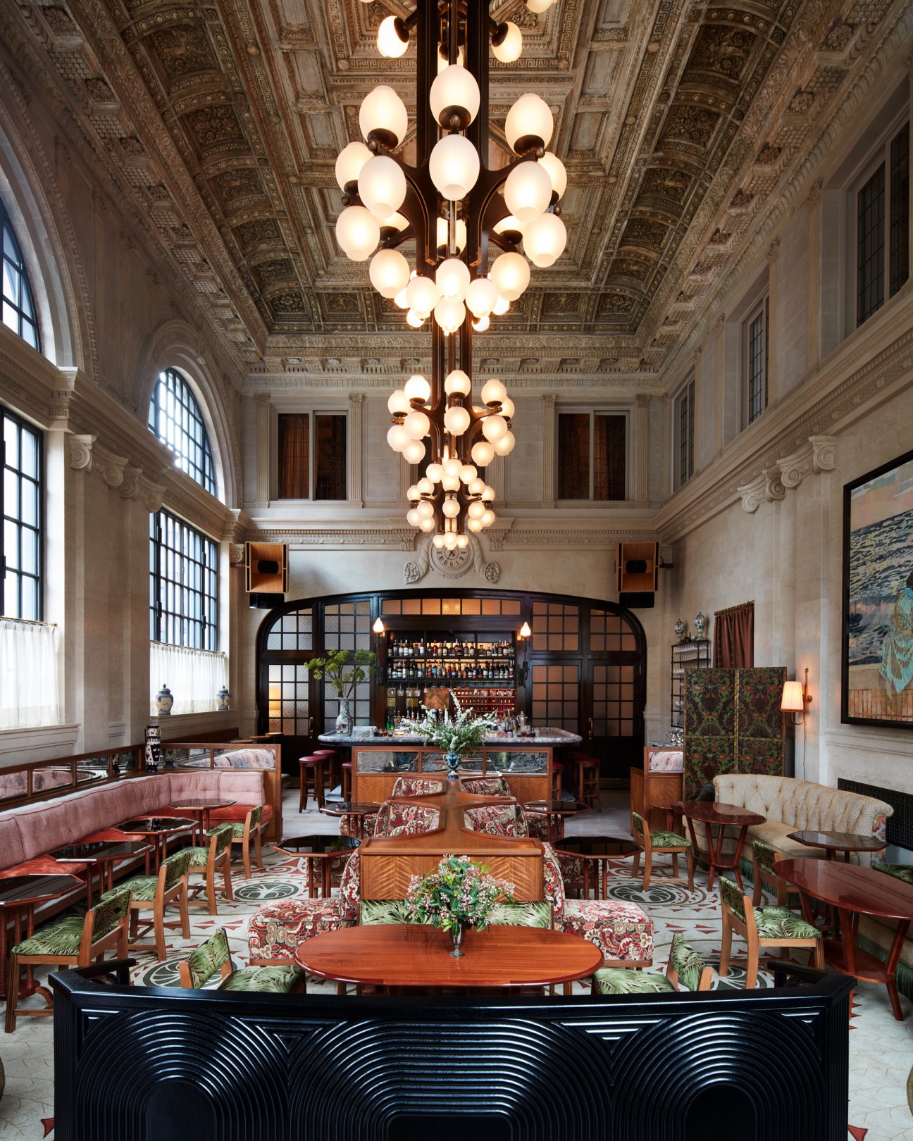 Elegant restaurant interior with ornate coffered ceiling, large chandeliers, and dining tables with upholstered seating