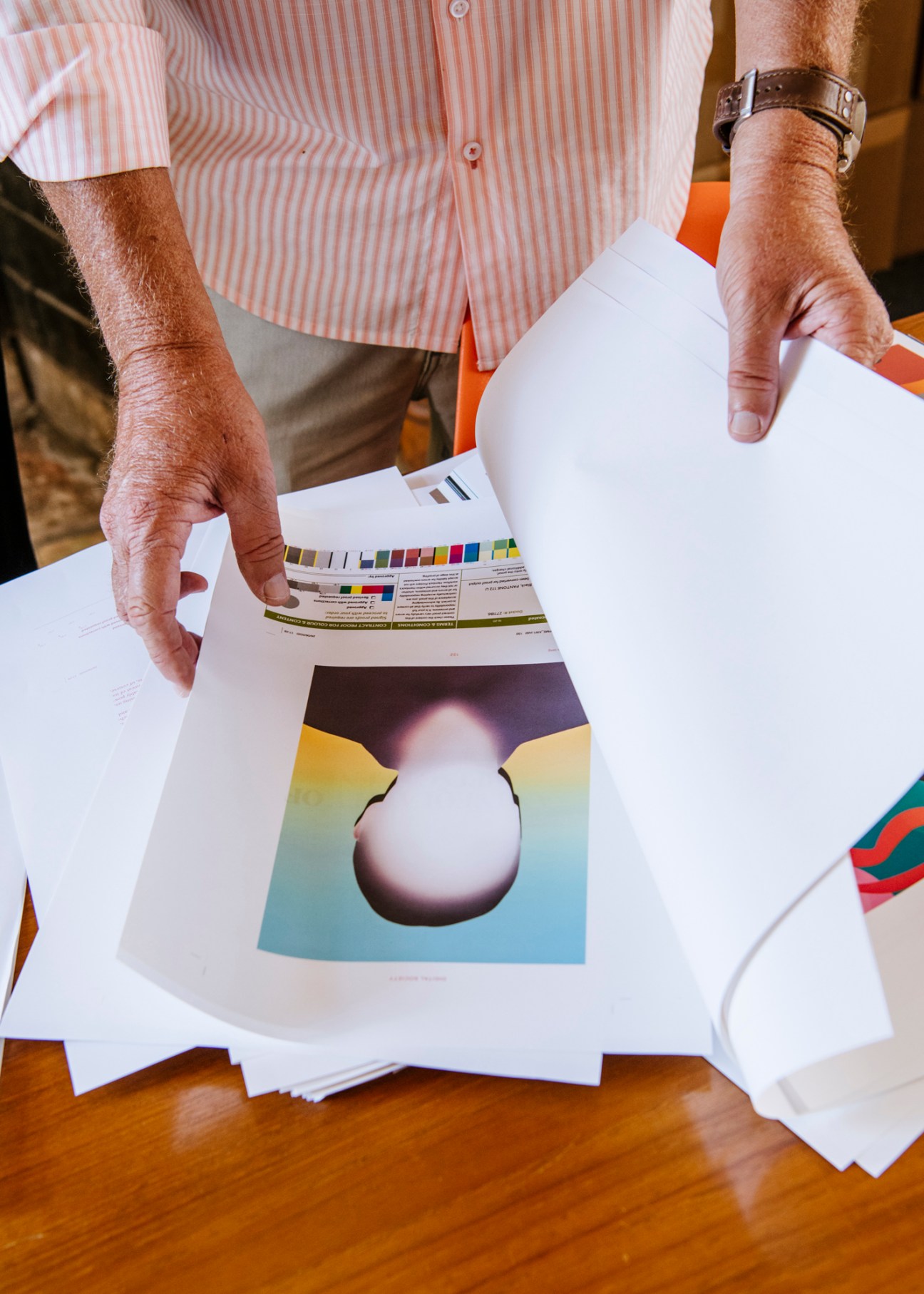 Hands examining printed proofs and color calibration sheets during Noema magazine production process