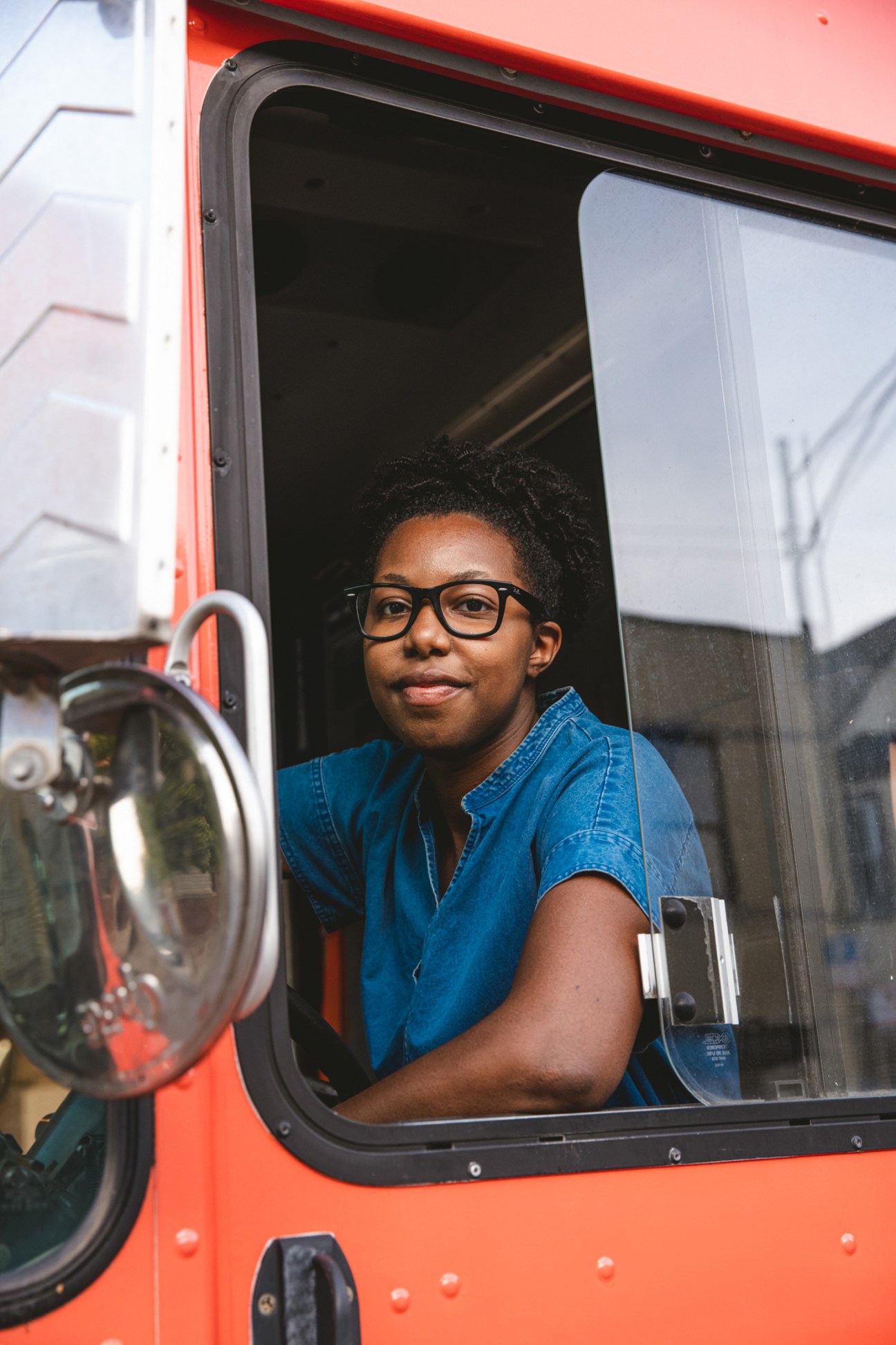 Person with glasses and denim shirt sitting inside Mobile Makers workshop truck